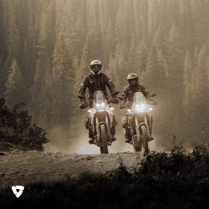 Adventure riding style - two adventure riders on dusty forest trail